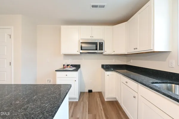 a kitchen with granite countertop white cabinets and stainless steel appliances