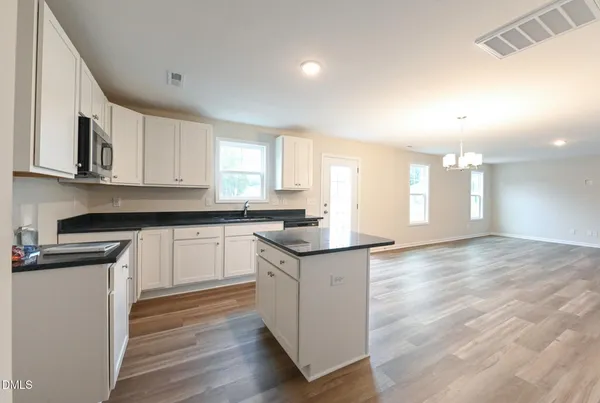 a kitchen with granite countertop a sink and cabinets with wooden floor