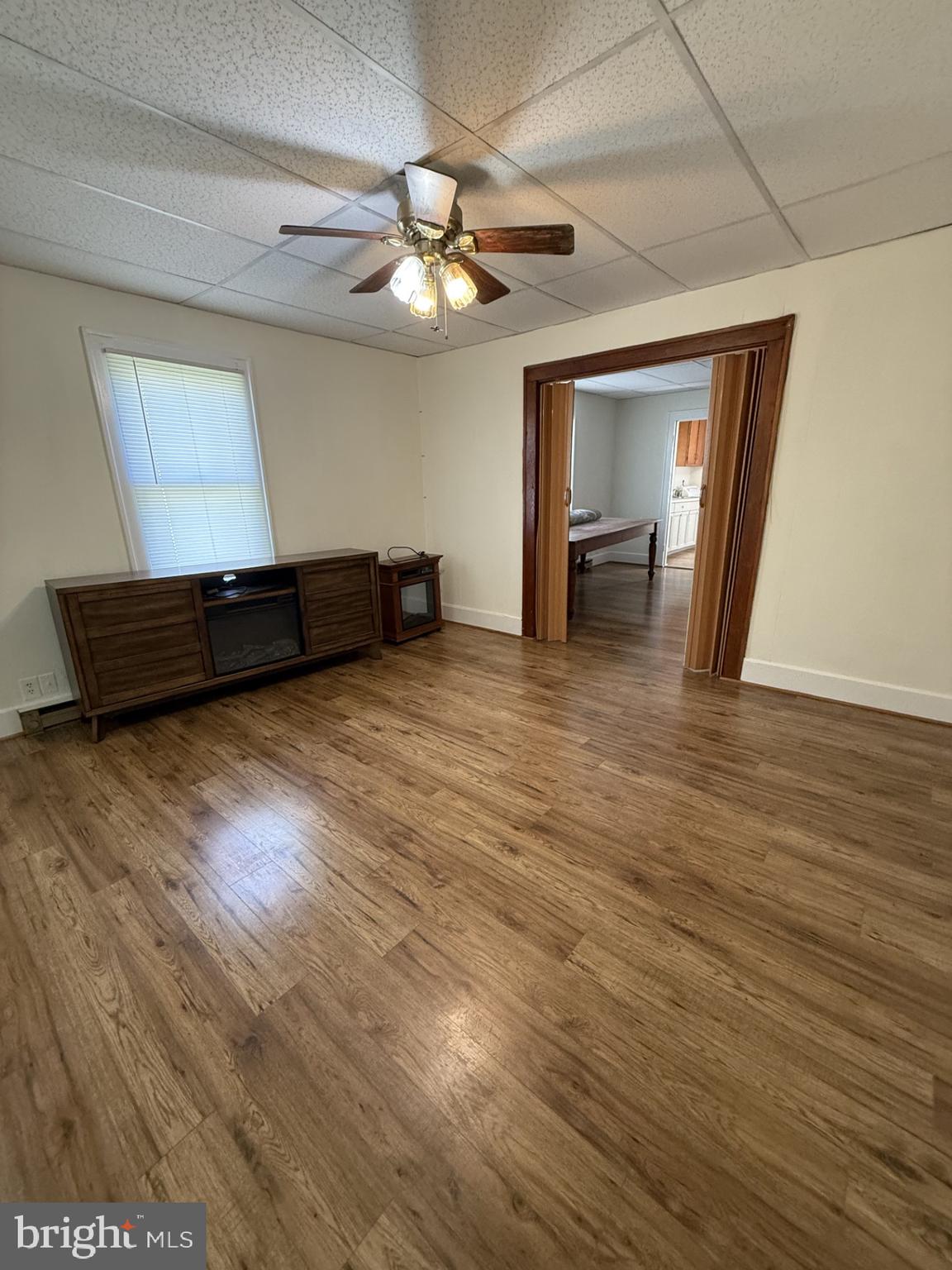 5497 Rosedale Drive King George, VA 22485 - Photo 7 of 12 an empty room with wooden floor chandelier fan and windows