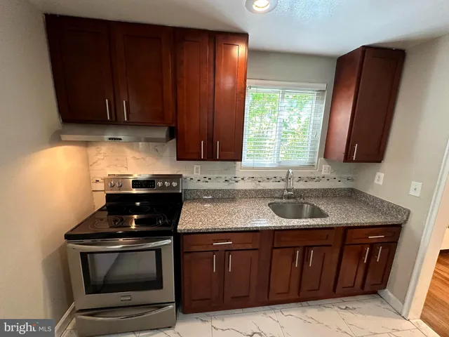 a kitchen with granite countertop a sink stove and cabinets