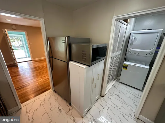 a view of a refrigerator in kitchen and an empty room