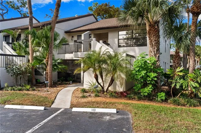 a view of a house with potted plants and palm trees