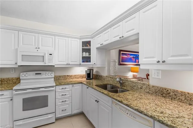 a kitchen with granite countertop white cabinets and white appliances