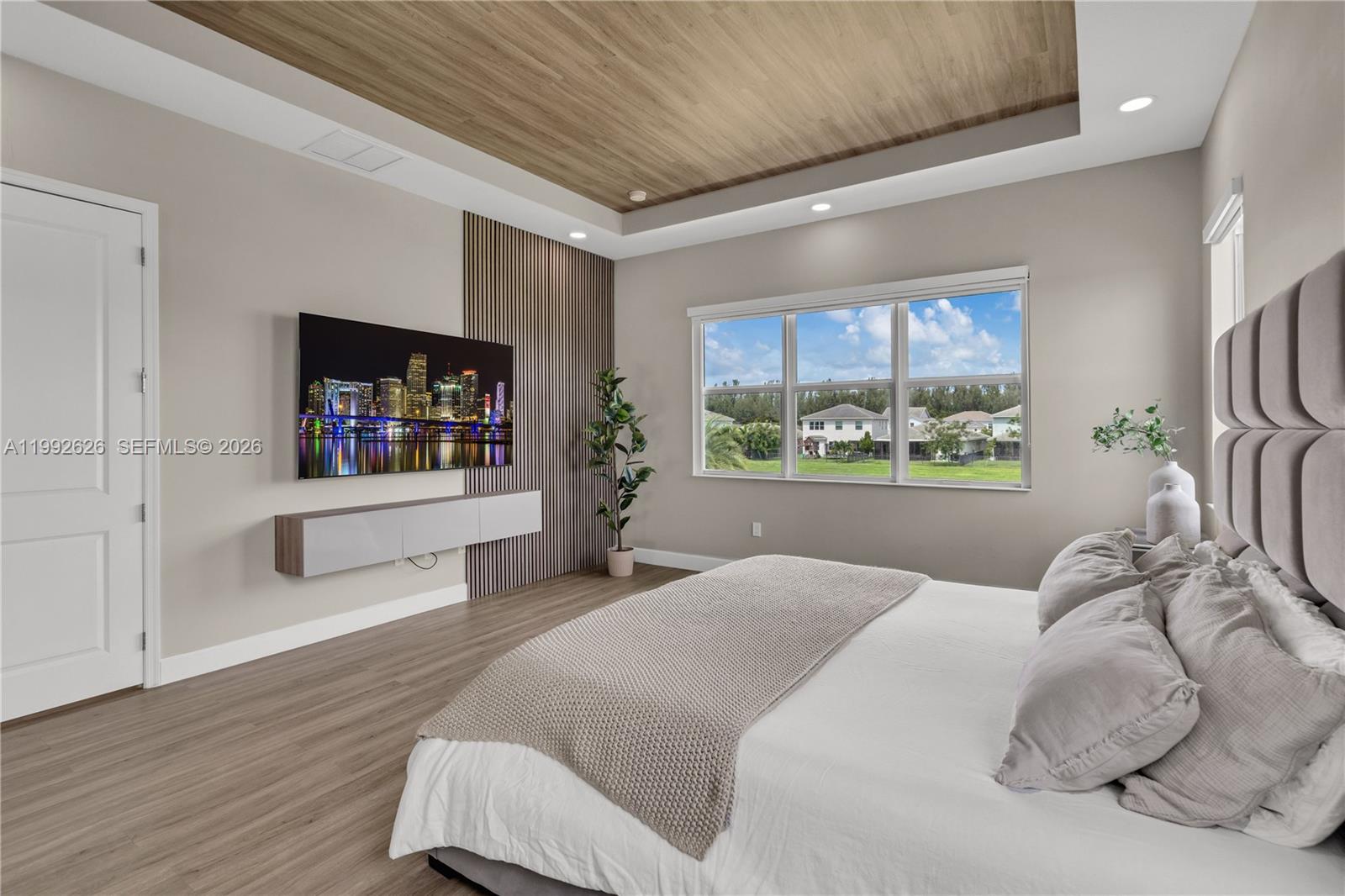 15769 Hummingbird Lane Loxahatchee, FL 33470 - Photo 33 of 54 a bedroom with a large bed and a flat tv screen on dresser