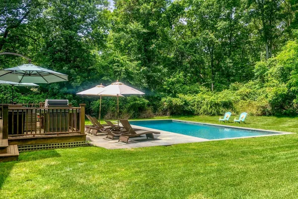 a view of a swimming pool with a table and chairs under an umbrella