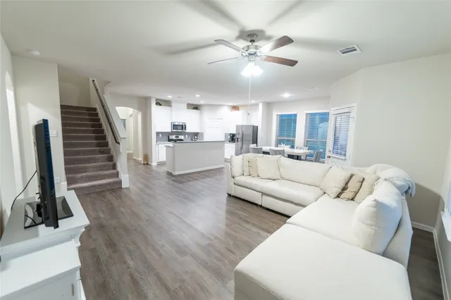 a living room with furniture kitchen view and a wooden floor