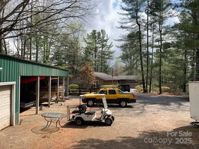 a view of a patio with table and chairs under an umbrella with large trees