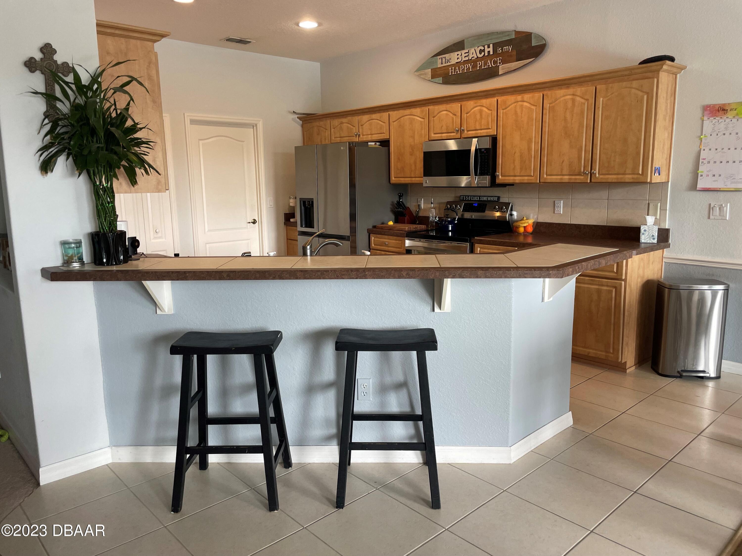 6129 Pheasant Ridge Drive Port Orange, FL 32128 - Photo 14 of 25 a kitchen with stainless steel appliances a table and chairs in it