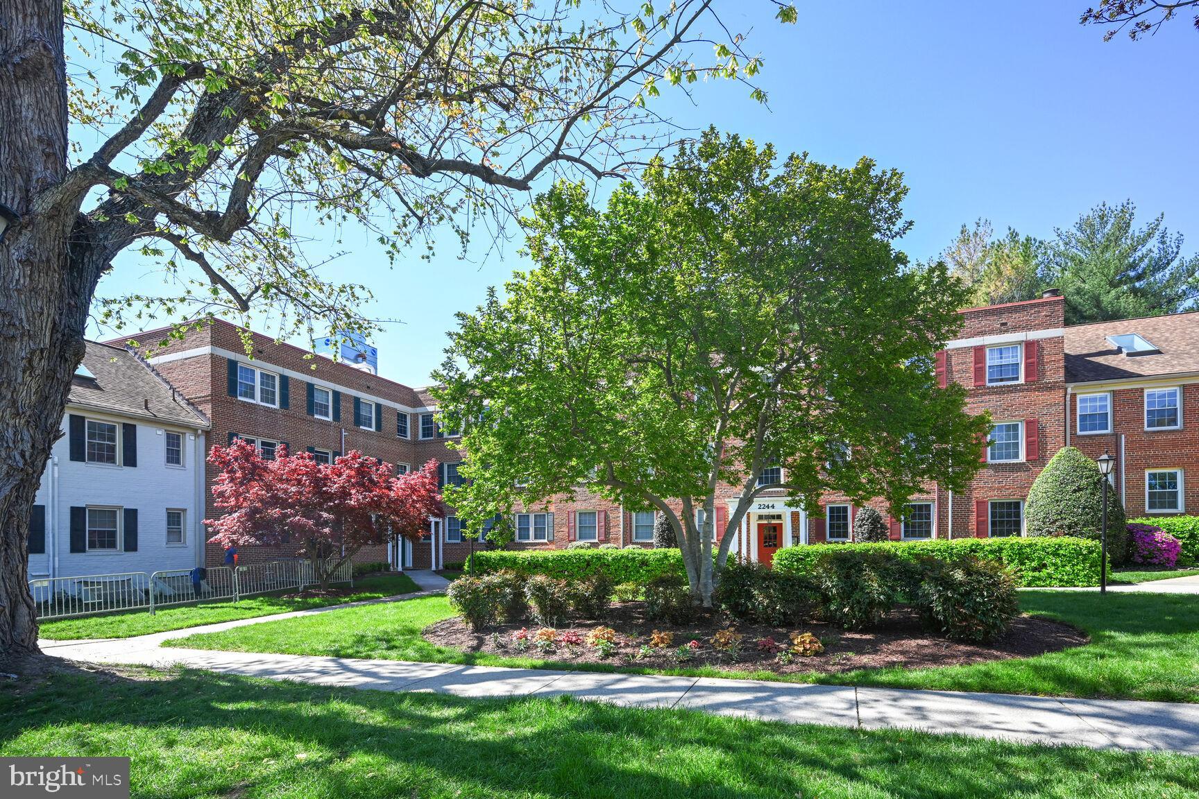 a front view of a building with a garden and trees