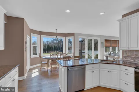 a kitchen with granite countertop a stove and white cabinets with wooden floors