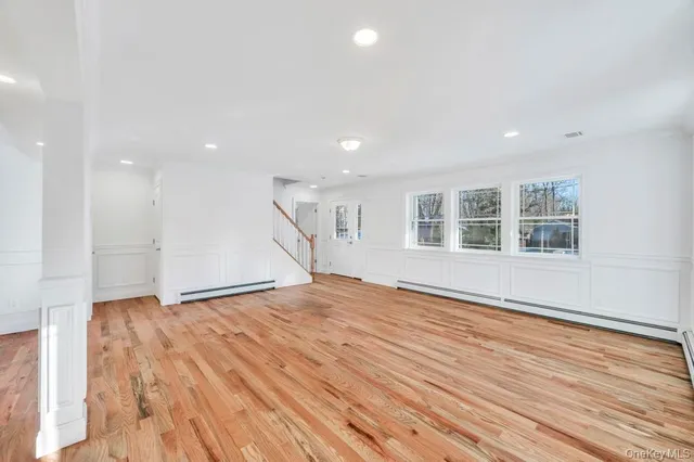 a view of empty room with wooden floor and windows