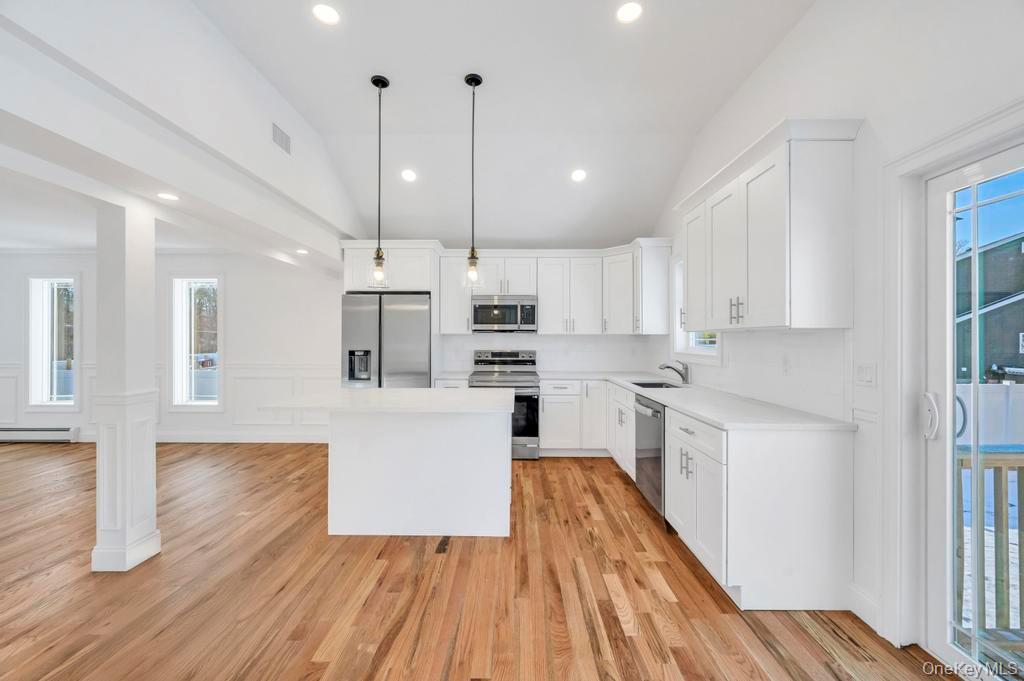 49 Barclay Road Mastic Beach, NY 11951 - Photo 16 of 33 a kitchen with wooden floors and white cabinets