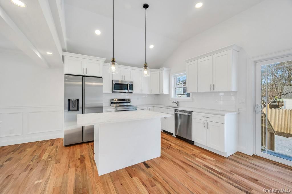49 Barclay Road Mastic Beach, NY 11951 - Photo 17 of 33 a kitchen with stainless steel appliances white cabinets a sink a stove a refrigerator and white cabinets with wooden floor