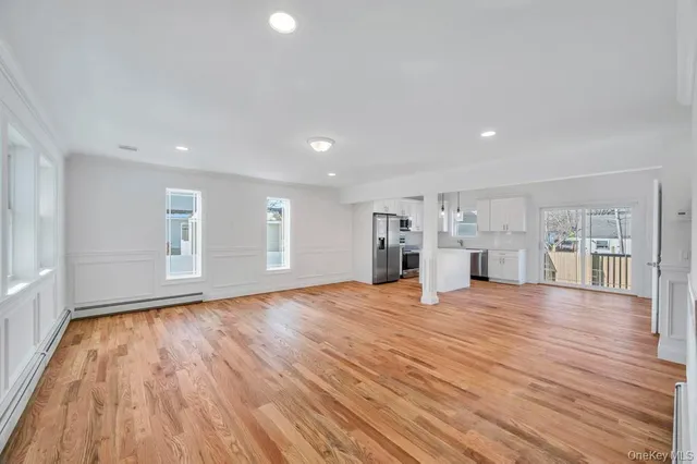 a view of empty room with wooden floor and window