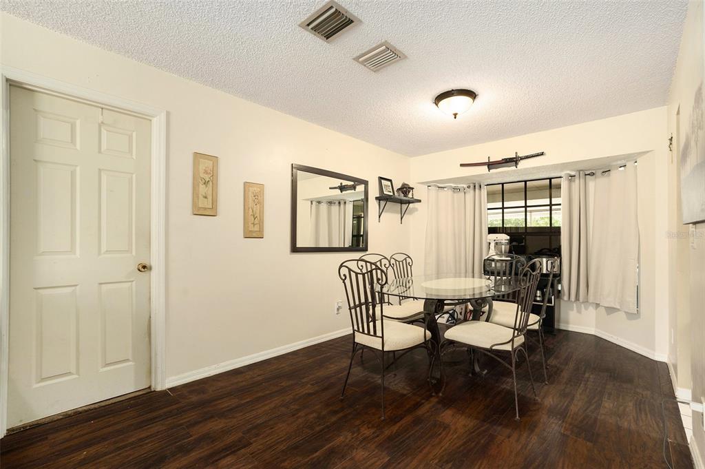 5960 Boyette Road Wesley Chapel, FL 33543 - Photo 6 of 32 a dining room with wooden floor a chandelier a wooden table and chairs