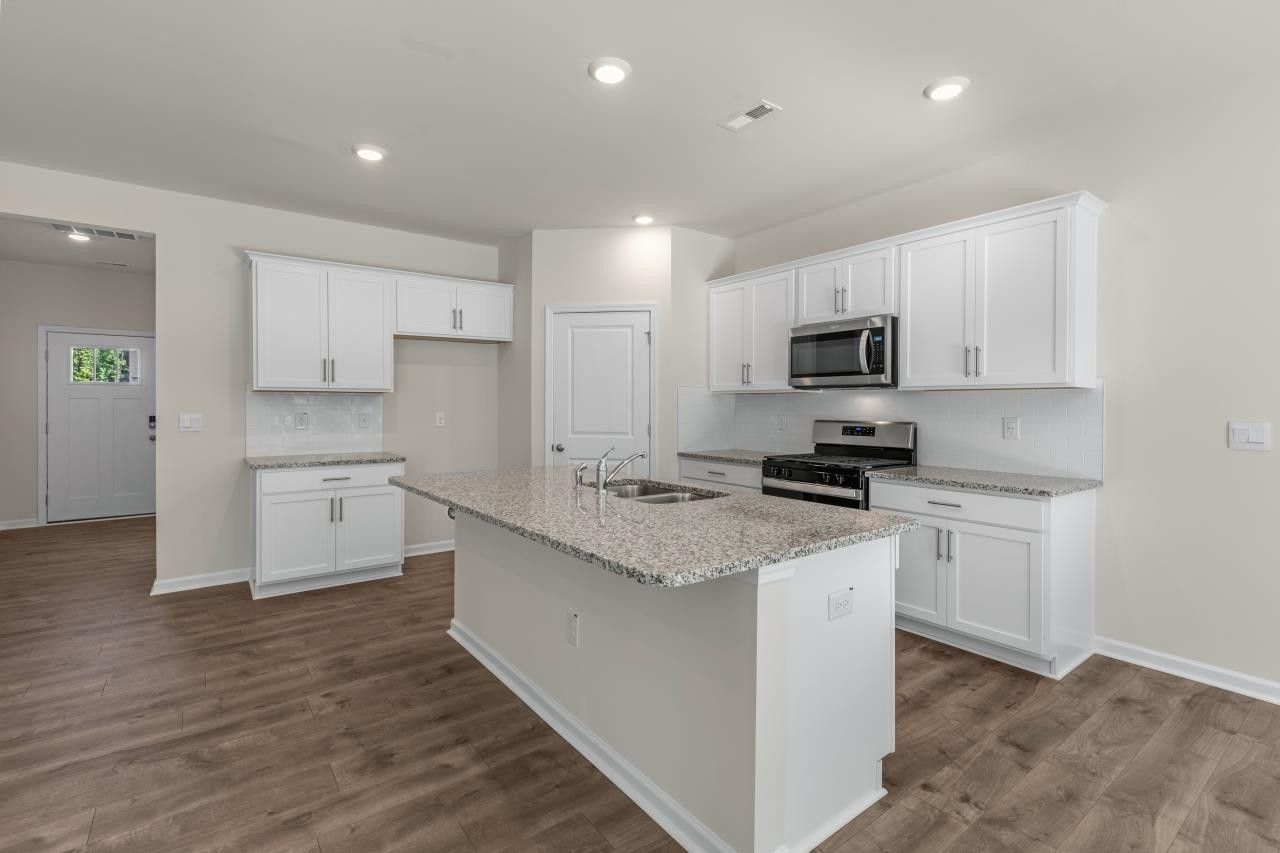2129 Clydesmill Road Fayetteville, NC 28314 - Photo 15 of 37 a kitchen with a sink a stove a microwave a center island and a window