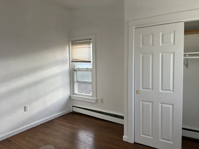 an empty room with wooden floor cabinet and windows