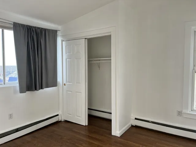 an empty room with wooden floor and window