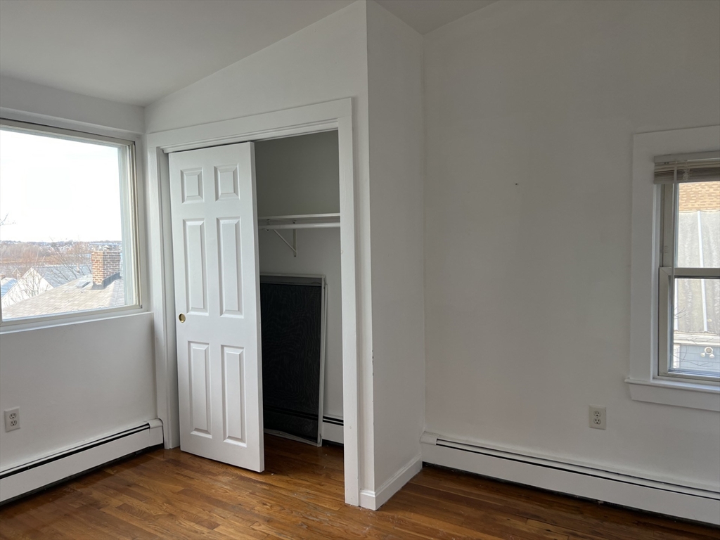 49 R Siren Street, Unit 3 Winthrop, MA 02152 - Photo 10 of 12 an empty room with wooden floor cabinet and windows