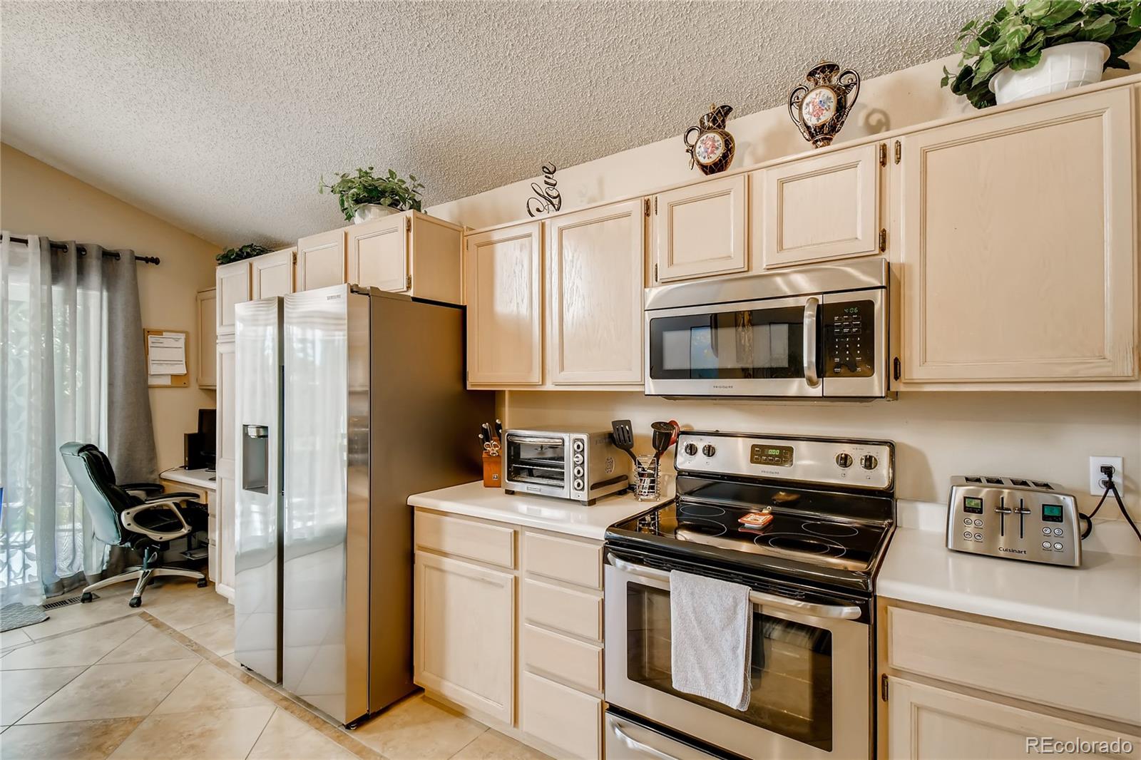 9879 Concord Court Highlands Ranch, CO 80130 - Photo 10 of 36 a kitchen with stainless steel appliances a refrigerator stove and microwave