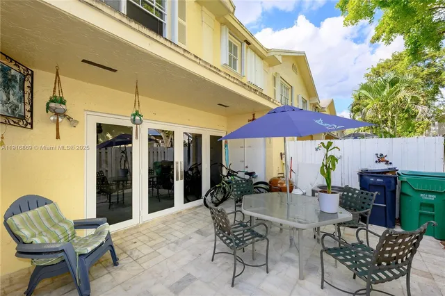 a patio with a table and chairs and potted plants
