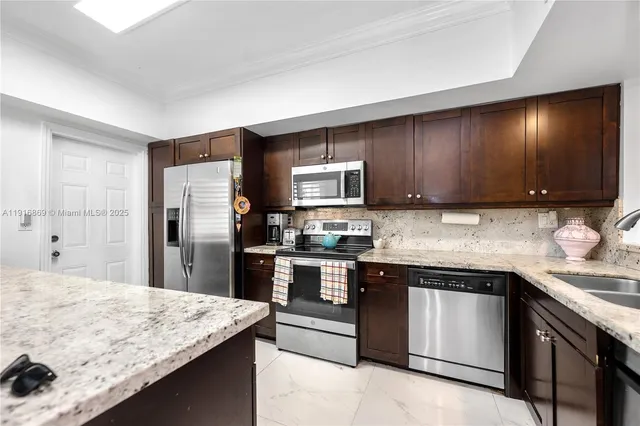 a kitchen with stainless steel appliances granite countertop a sink stove microwave and refrigerator