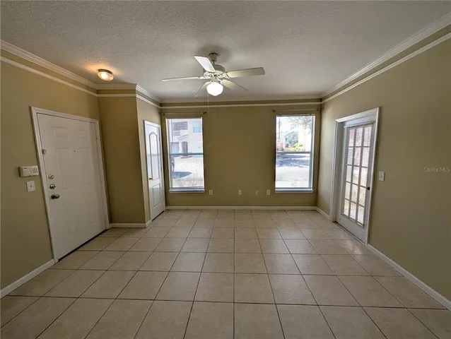 a view of an empty room with window and chandelier fan