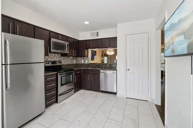 a kitchen with stainless steel appliances a refrigerator sink and microwave