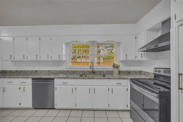 a kitchen with granite countertop white cabinets and white stainless steel appliances