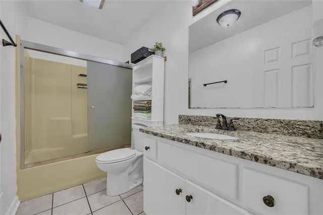 a bathroom with a granite countertop sink a toilet and a shower