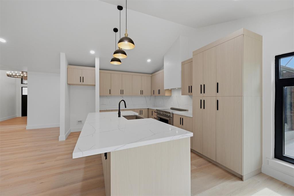 410 Arkansas Road Sadler, TX 76264 - Photo 15 of 40 Kitchen featuring an expansive island with a waterfall countertop, light wood-finish cabinetry, stainless steel appliances, a white tile backsplash, and recessed lighting