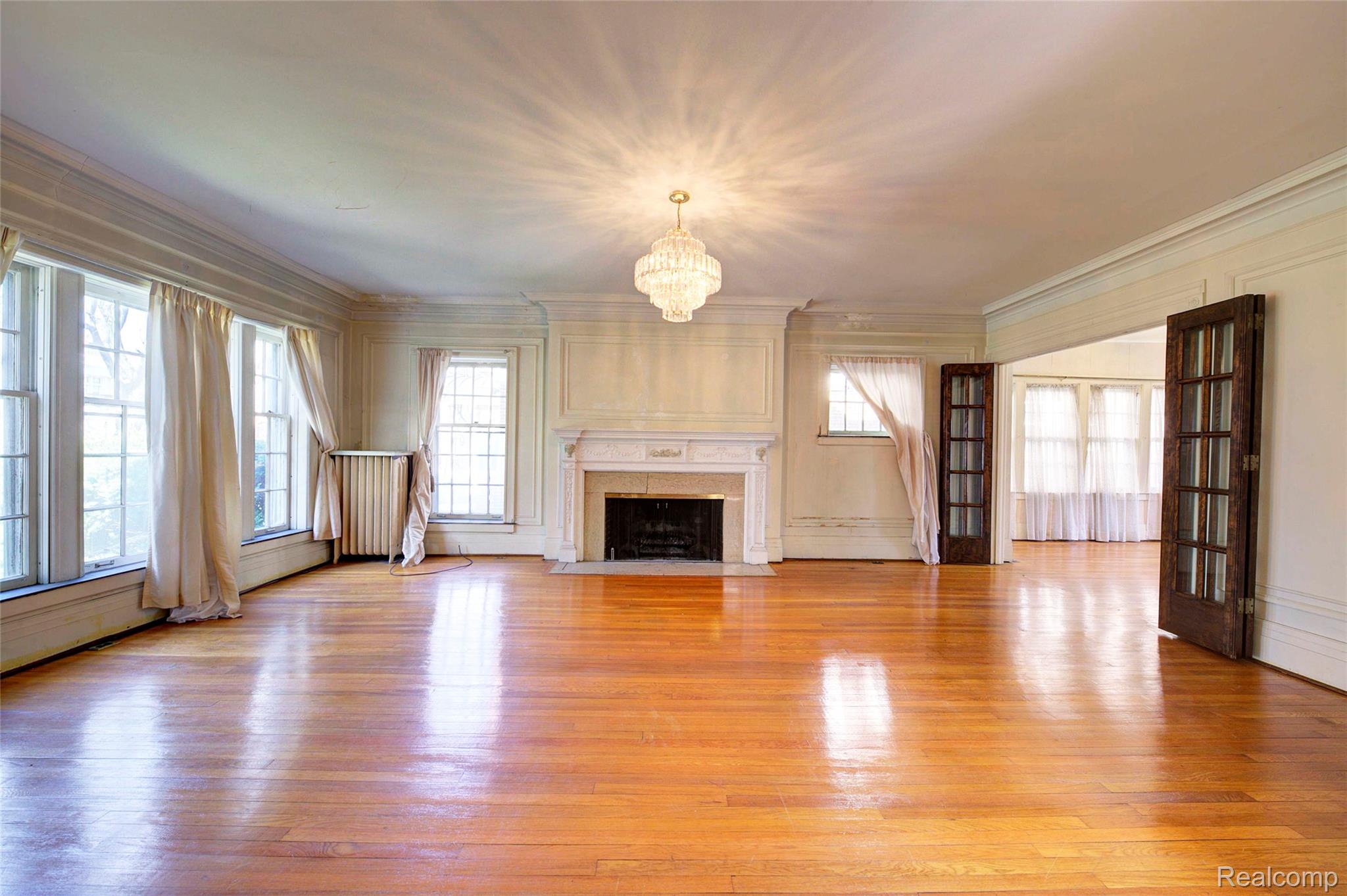 121 Longfellow Street Detroit, MI 48202 - Photo 11 of 87 Unfurnished living room with hanging lights, a high end fireplace, light wood-type flooring, and ornamental molding