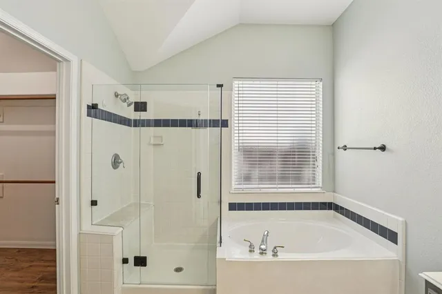 a bathroom with a tub shower and a window