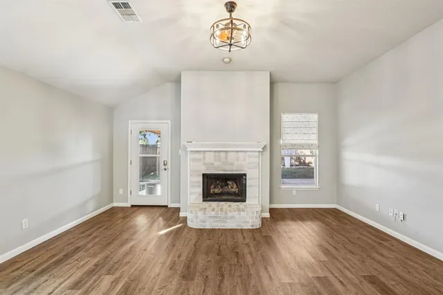 wooden floor fireplace and windows in an empty room