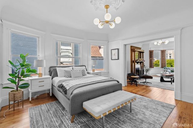 a bedroom with a bed couches chandelier and wooden floor