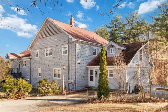 a view of a brick house with a small yard plants and large tree