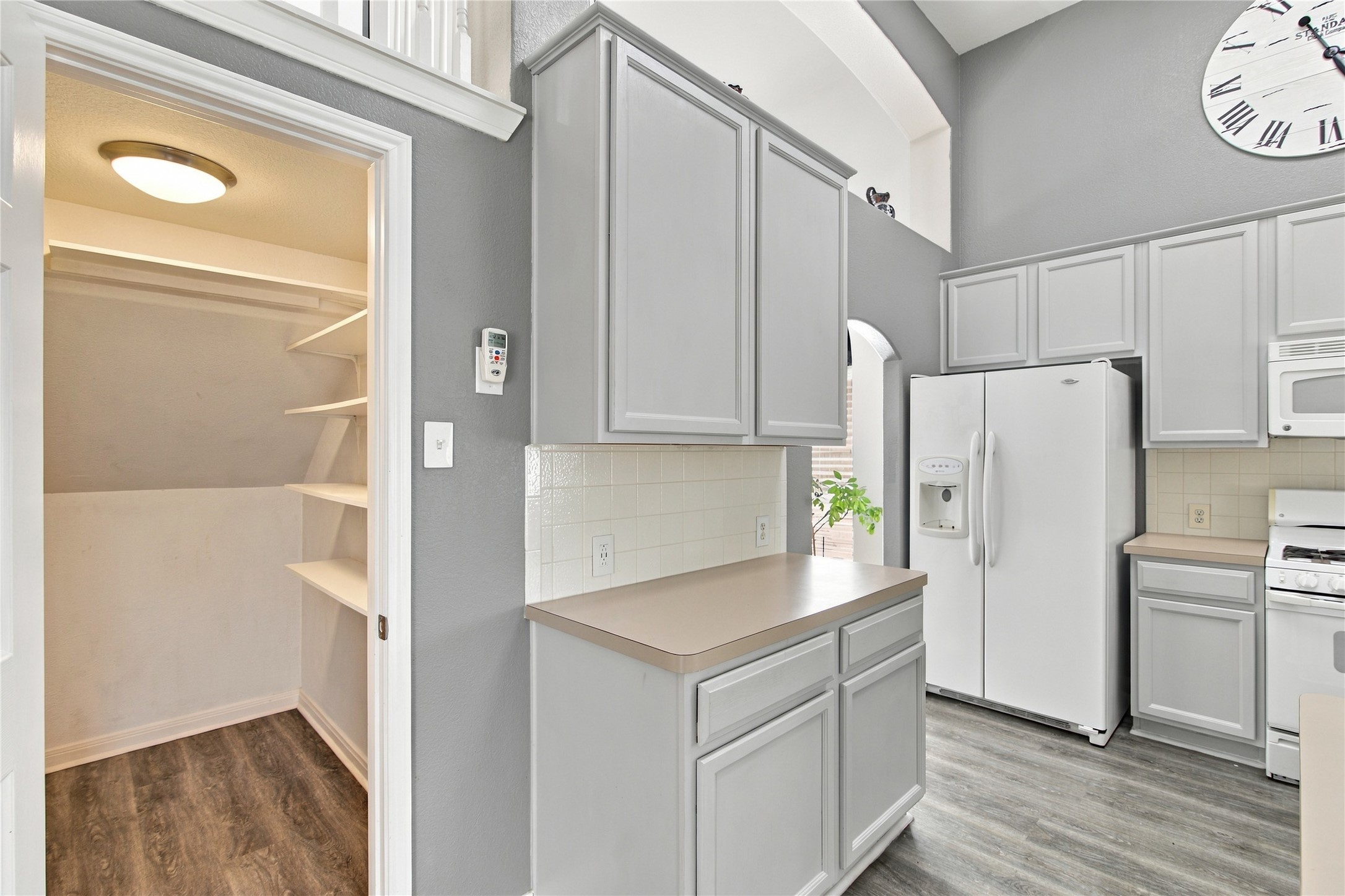 910 Point Run Drive Pflugerville, TX 78660 - Photo 12 of 39 High ceilings and durable wood-look flooring enhance this functional kitchen layout with adjacent pantry storage.