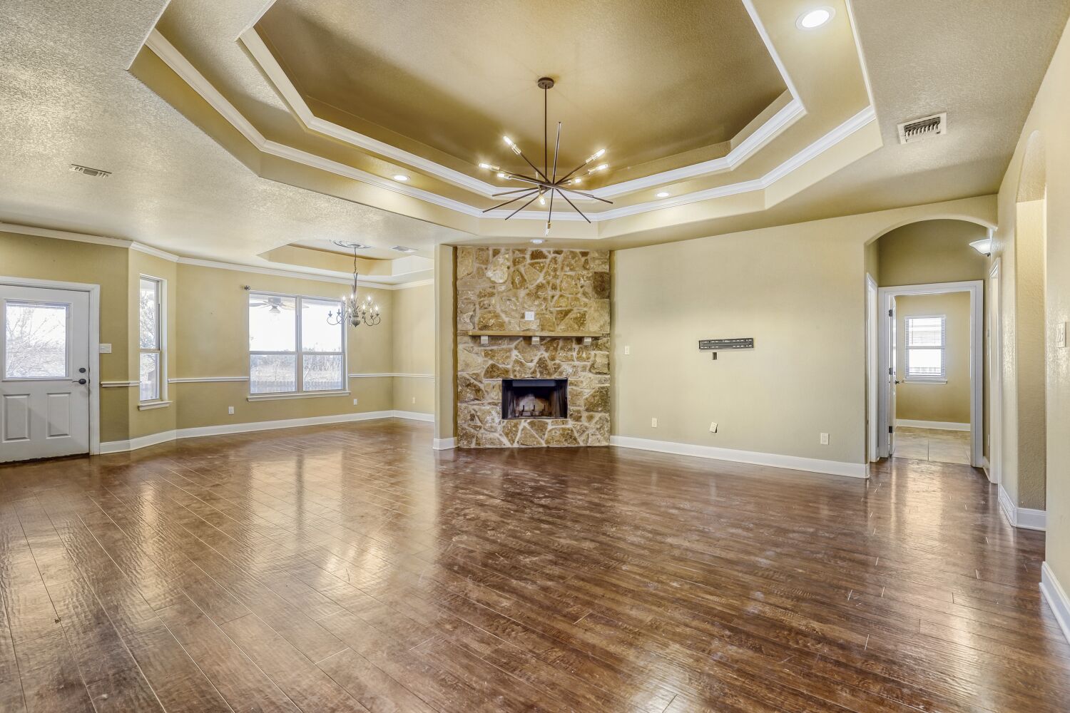 329 Jake Drive Jarrell, TX 76537 - Photo 3 of 17 Unfurnished living room with a chandelier, crown molding, a fireplace, dark wood-type flooring, and arched walkways