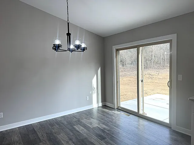 a large white kitchen with granite countertop a large counter top space and stainless steel appliances