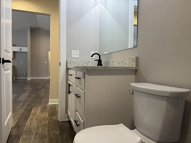 a bathroom with a granite countertop sink toilet a mirror and shower