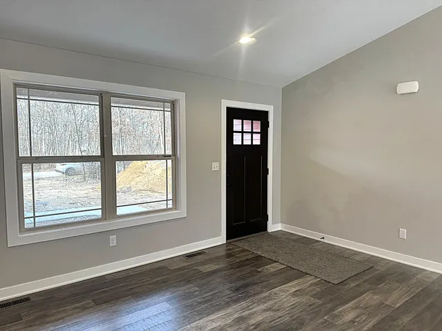 a view of an empty room with window and wooden floor