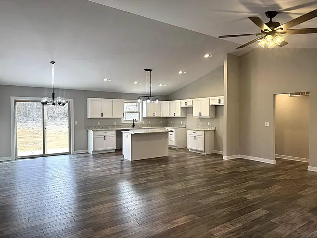 a view of a livingroom with wooden floor a ceiling fan and windows