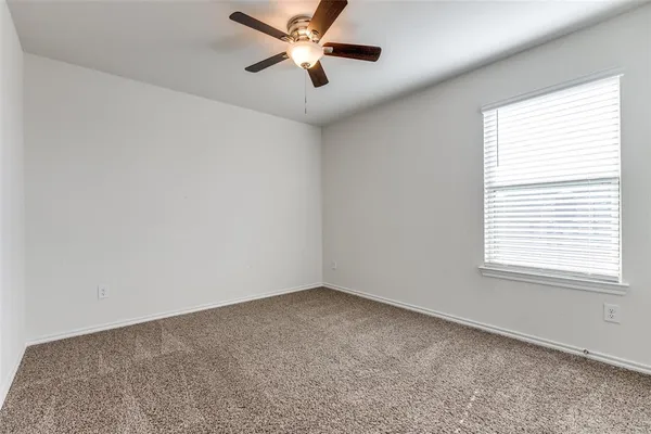 an empty room with a window and a fan