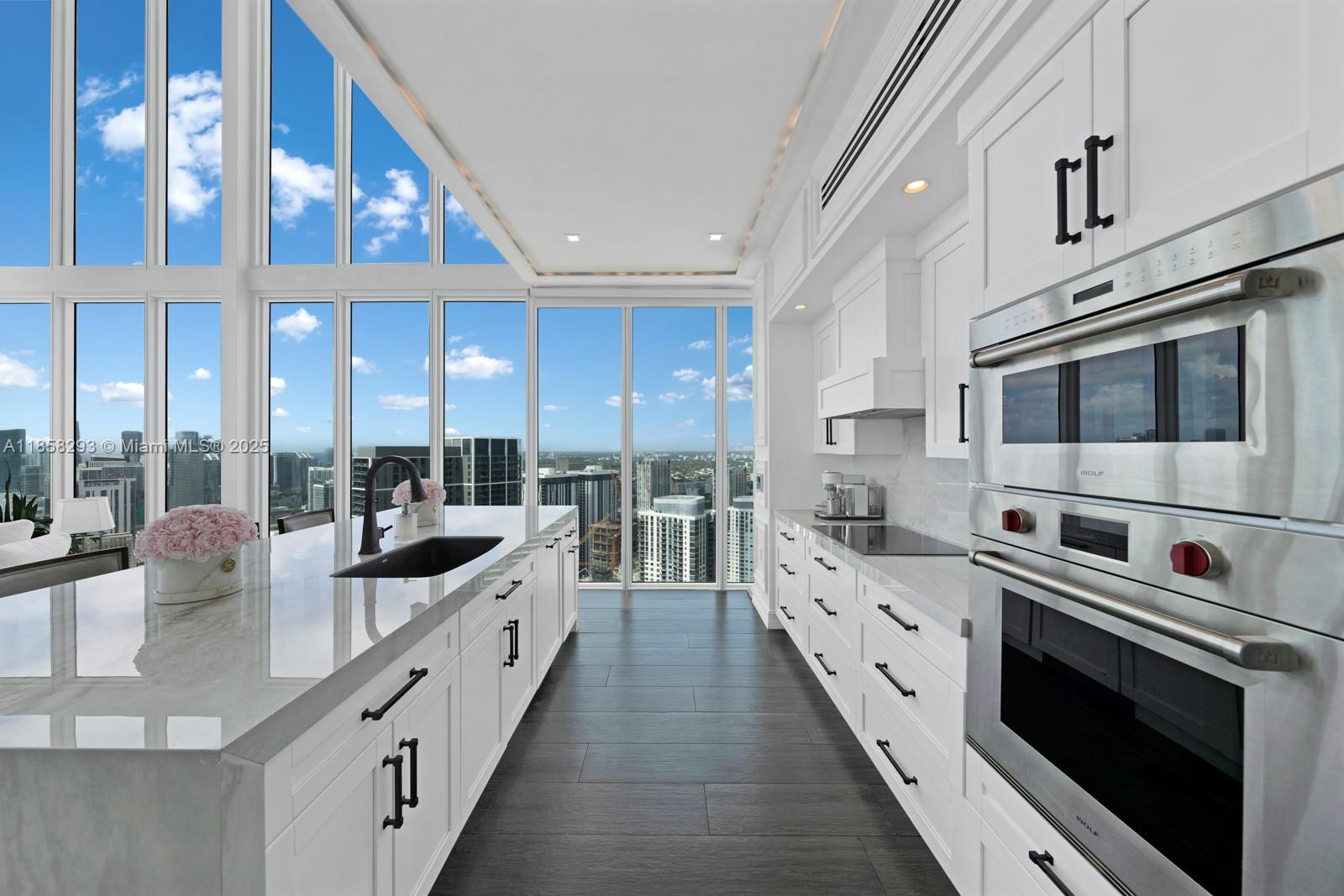 888 Biscayne Boulevard, Unit 5701 Miami, FL 33132 - Photo 4 of 35 a large white kitchen with stainless steel appliances and a large window