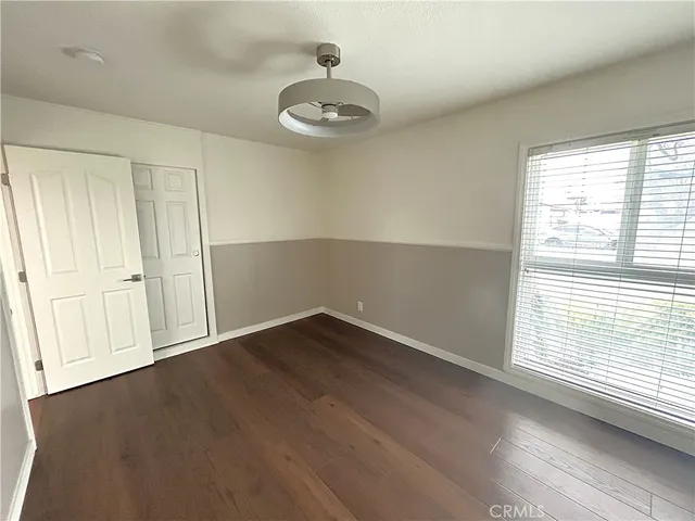 an empty room with wooden floor cabinet and windows