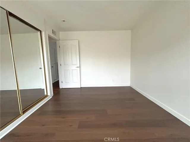 a view of an empty room with wooden floor and a glass door