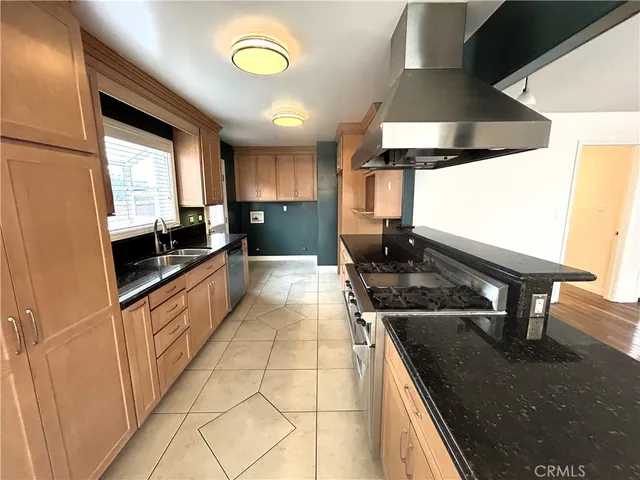 a kitchen with stainless steel appliances granite countertop a sink a stove and a wooden floors