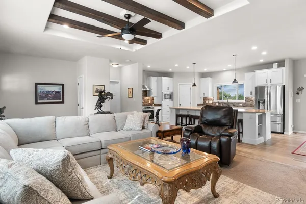 a living room with furniture kitchen view and a chandelier