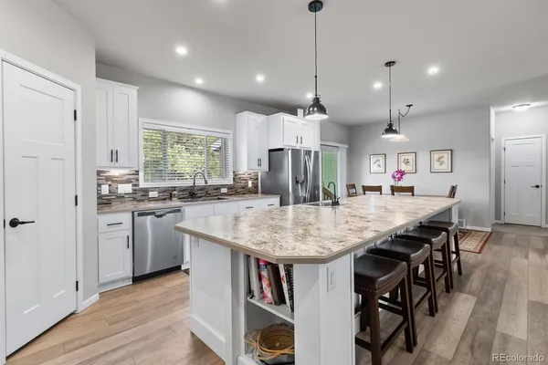 a kitchen with kitchen island a dining table chairs stainless steel appliances and cabinets