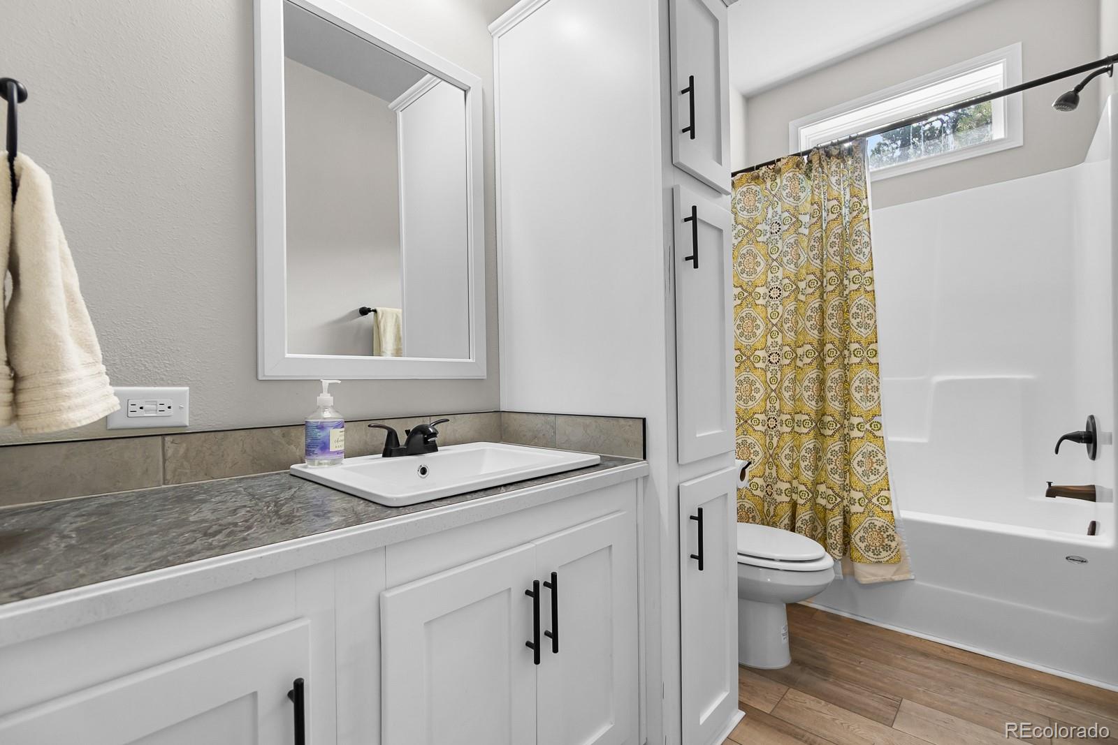 11374 Ridgewood Way Kiowa, CO 80117 - Photo 21 of 49 a bathroom with a granite countertop sink a toilet a mirror a vanity and shower